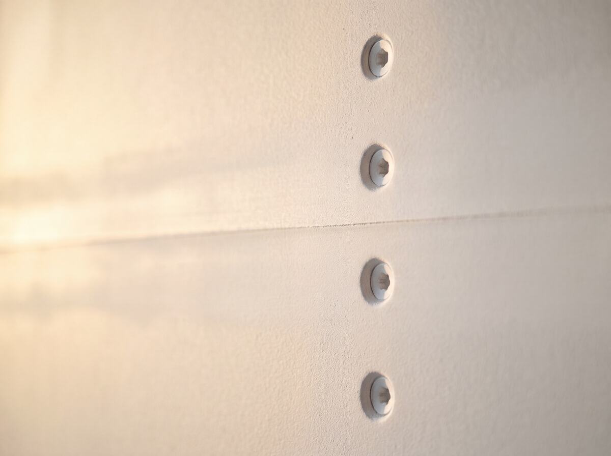 Detalhe de junta tratada e parafusos em pladur com acabamento liso e perfeito